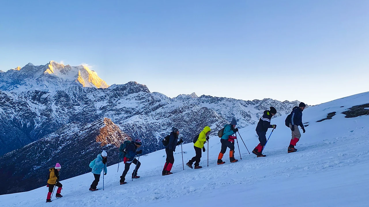 Group of trekkers ascending a snowy mountain, demonstrating the 'Climb High, Sleep Low' technique for altitude acclimatization